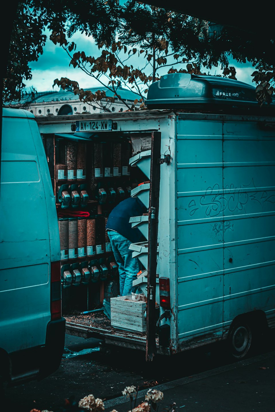 Worker organizes bulk dry goods inside a teal delivery van.
